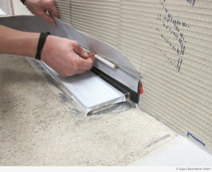 Übergang dichten: Das Flex-Dichtband mit Schlaufe wird mit dem Metallflansch der Rinne und den angrenzenden Baustoffen verklebt.