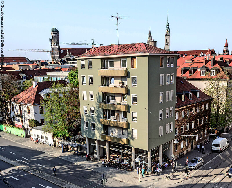 Grünes Wohnhaus an Straßenecke mit Frauenkirche im Hintergrund