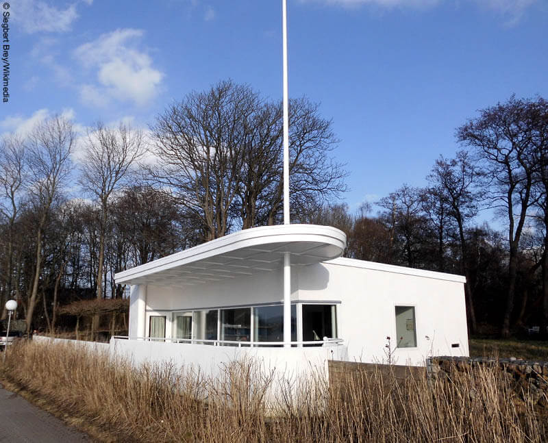 Weißes Wohnhaus mit Fahnenmast an der Kieler Förde