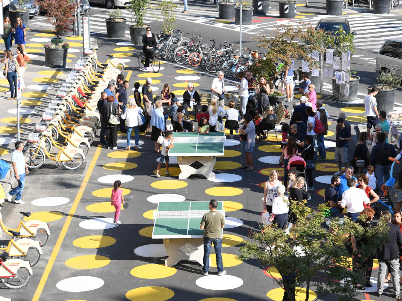 Menschen auf einem Platz mit gemalten Punkten auf dem Boden und Tischtennisplatten