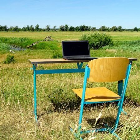 Schreibtisch mit Laptop inmitten eines ländlichen Felds