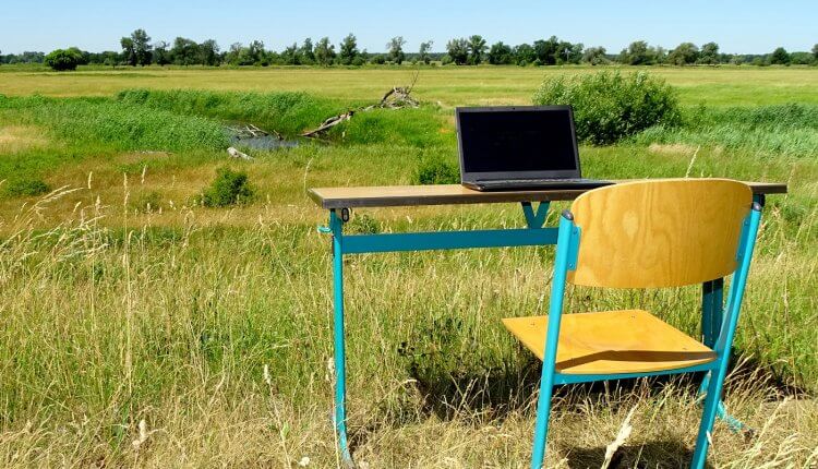 Schreibtisch mit Laptop inmitten eines ländlichen Felds