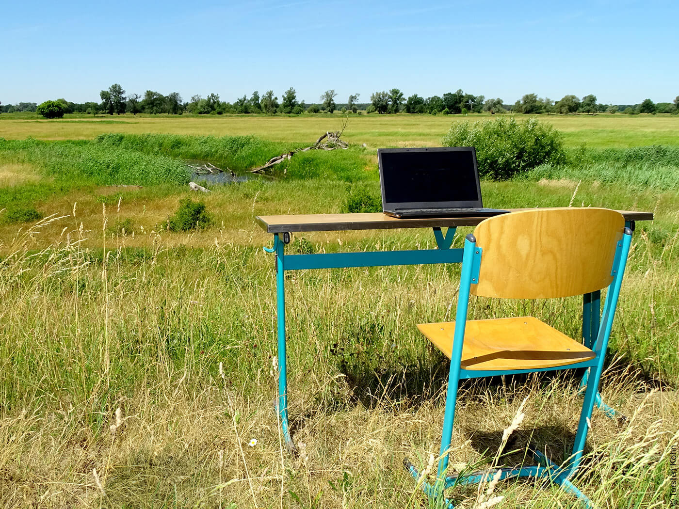 Schreibtisch mit Laptop inmitten eines ländlichen Felds