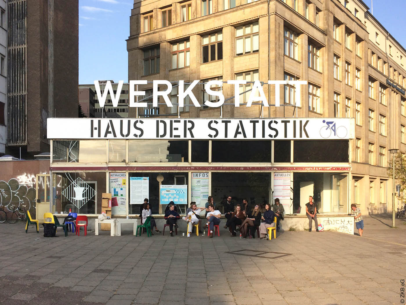 Personen sitzen vor der Werkstatt Haus der Statistik