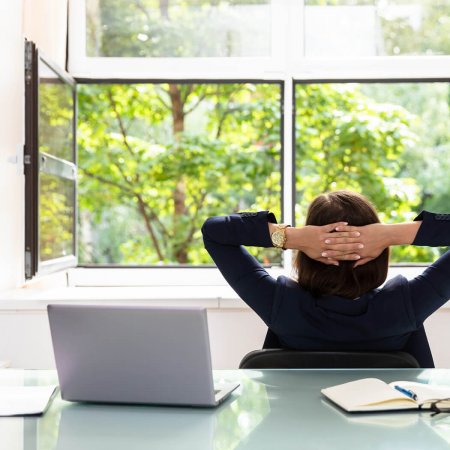 Frau am Schreibtisch genießt offenes Fenster