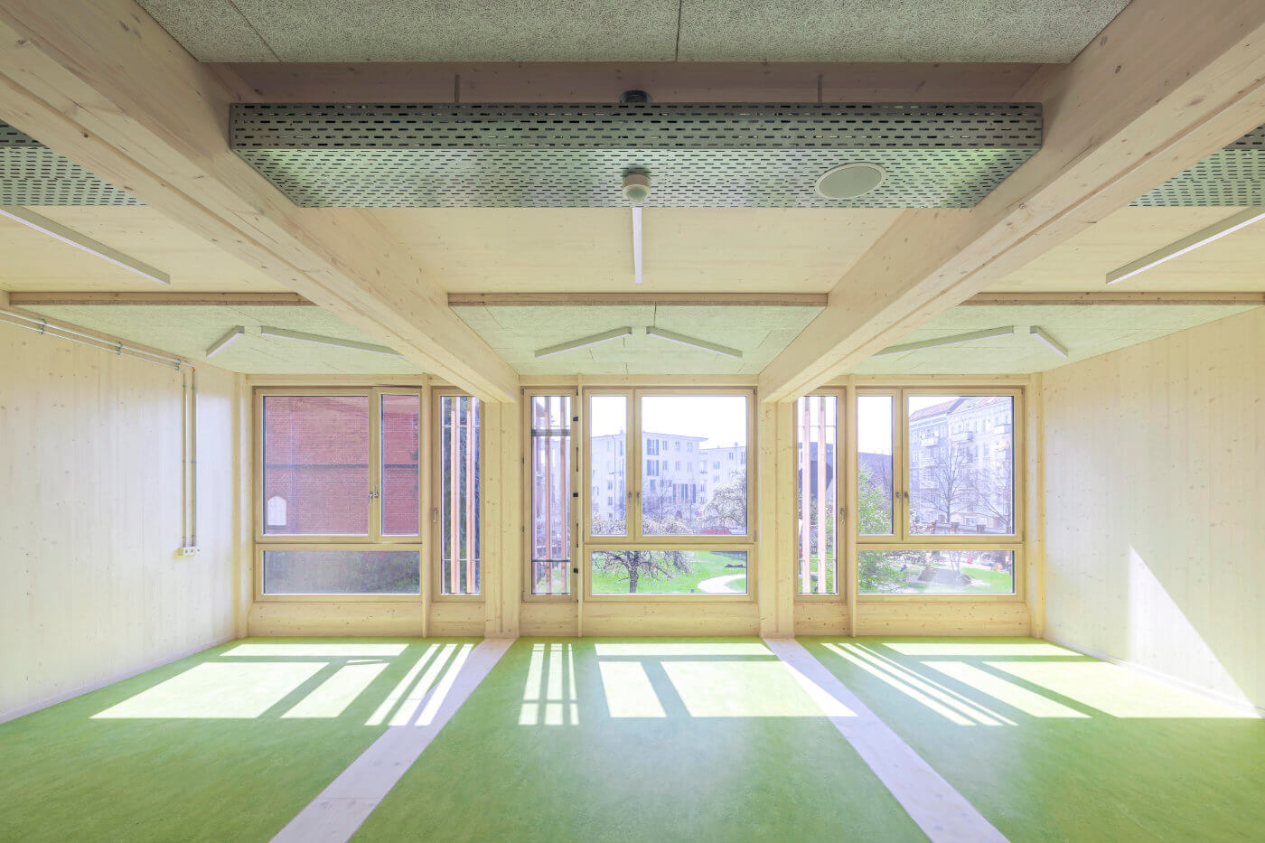 Klassenraum mit großen Fenstern und Holzdecke
