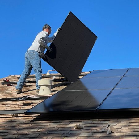 Mann montiert Solarzellen auf Dach