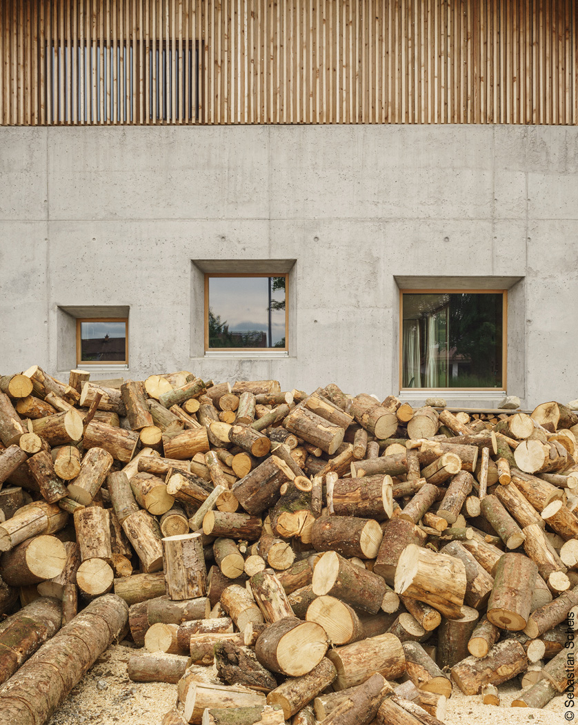 Holzhaufen vor Haus mit Betonfassade und Holzlamellen