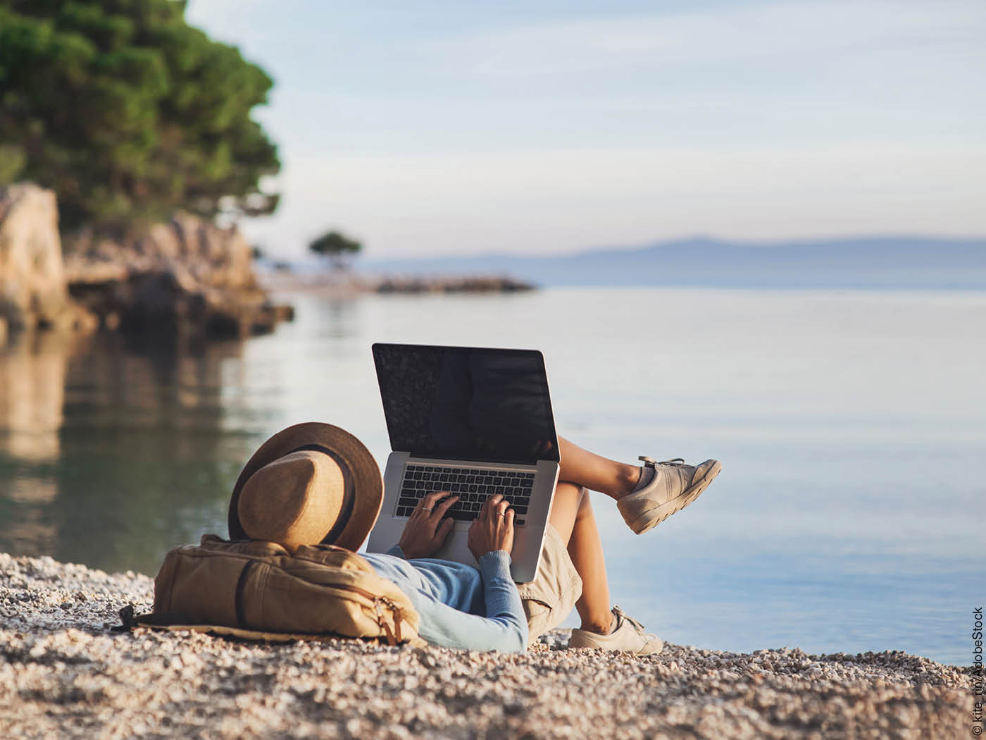 Frau liegt mit Laptop am Strand