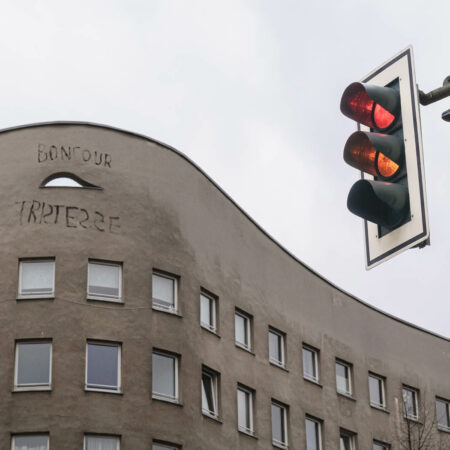 Wohnhaus mit grauer Fassade und Schriftzug Bonjour Tristesse