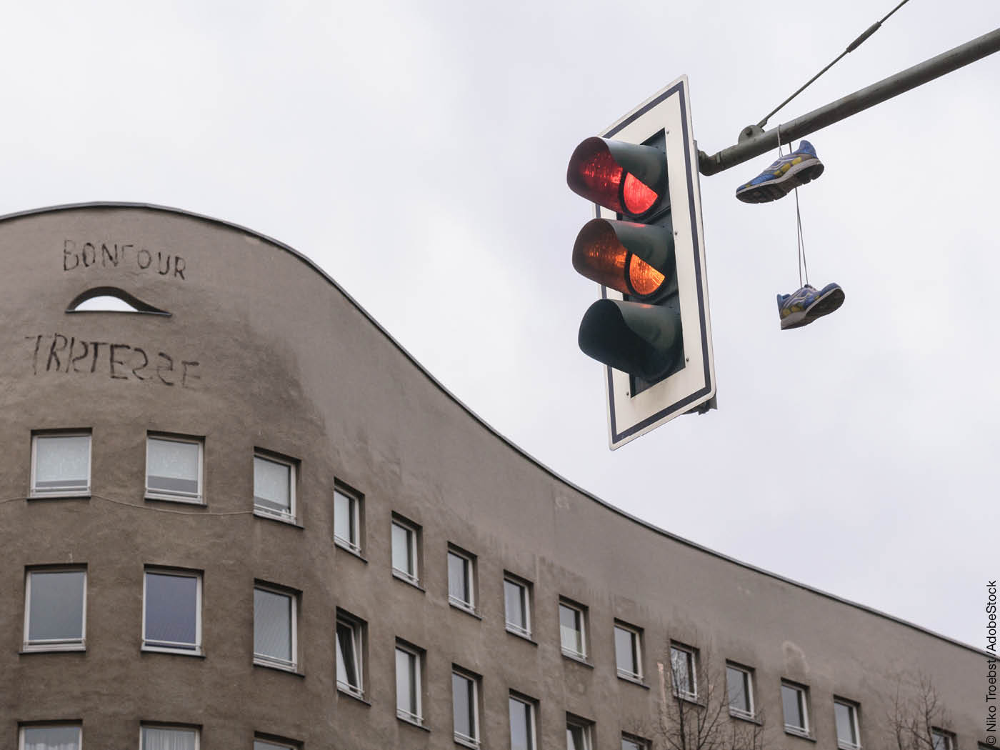 Ampel vor grauer Hausfassade mit der Aufschrift "Bonjour Tristesse"