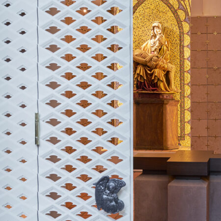 Weiße Gitterwand in Kirche mit Blick auf Statue