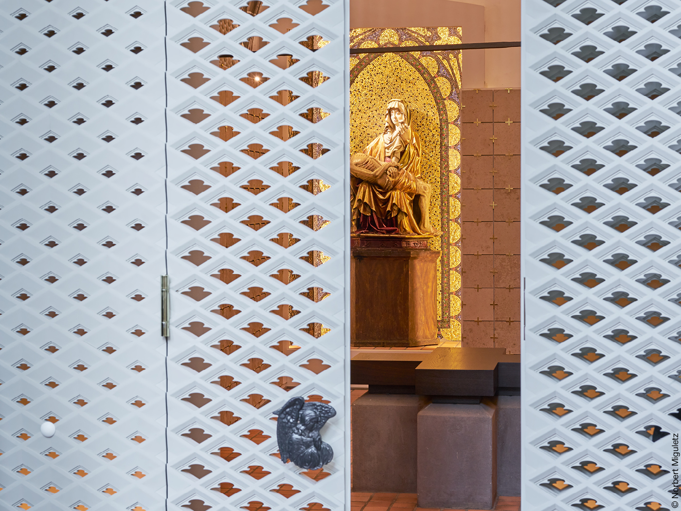 Weiße Gitterwand in Kirche mit Blick auf Statue