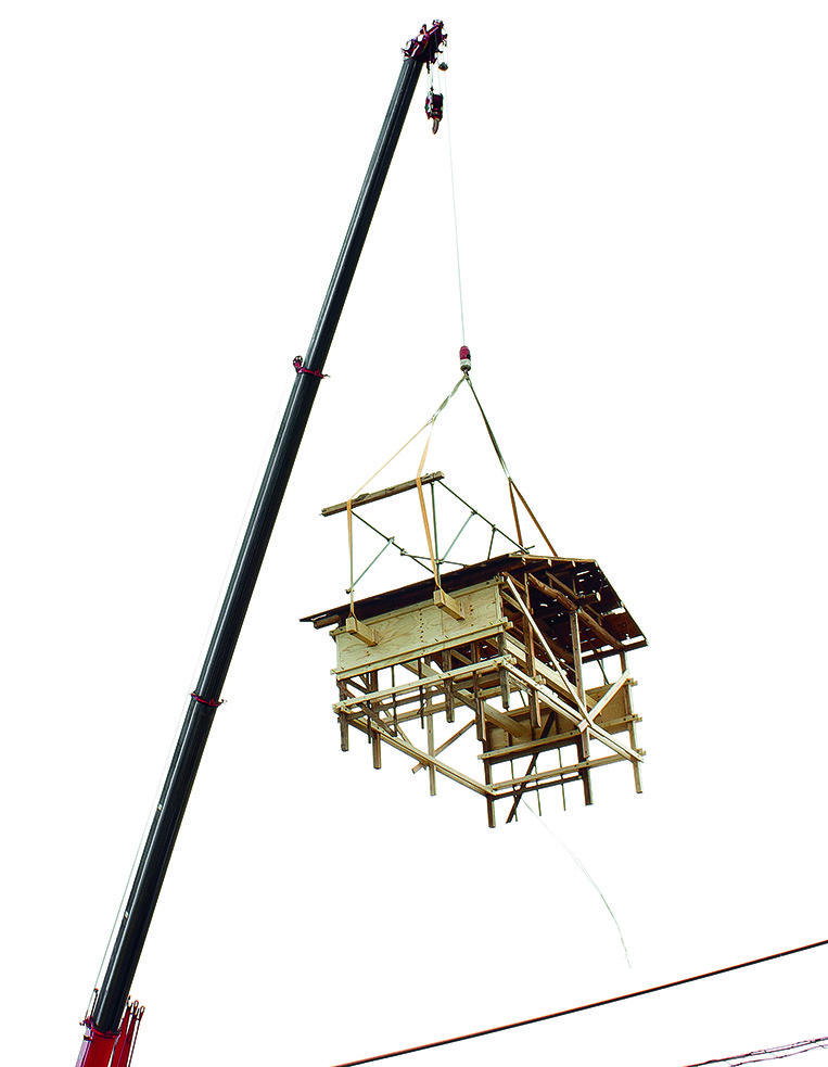 Kleines Holzhaus an Kran hängend