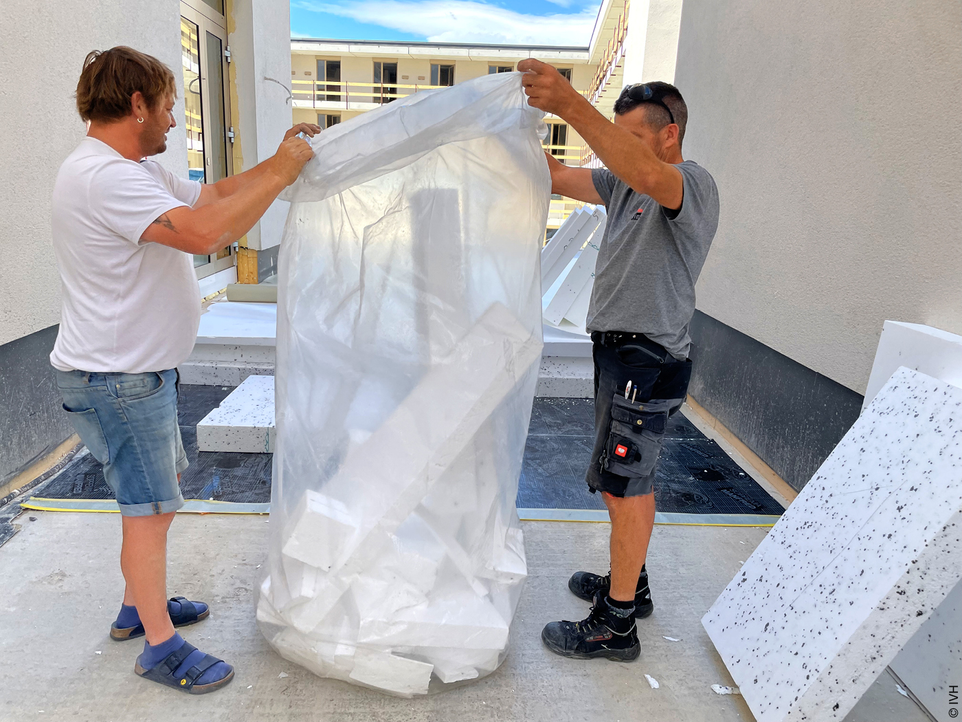 Zwei Männer verpacken Reste Gebäudedämmung zum Recycling