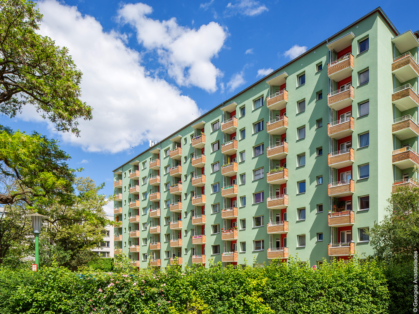 Grünes Wohngebäude mit Balkonen aus Klinker