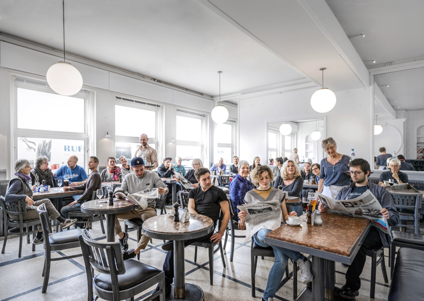 Menschen im Café Ruffini lesen Zeitung