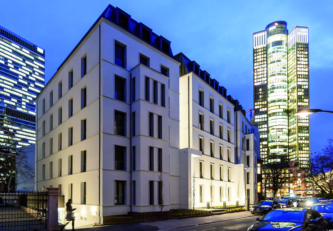 Mehrfamilienhaus am Abend mit Hochhaus im Hintergrund