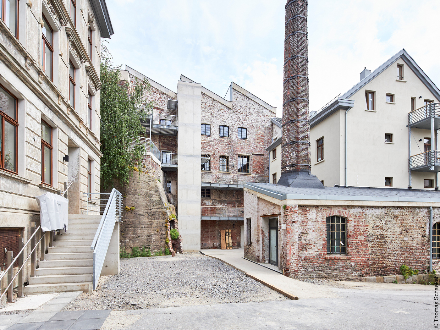 Sanierte Gründerzeithäuser und alte Fabrikhalle mit Schornstein