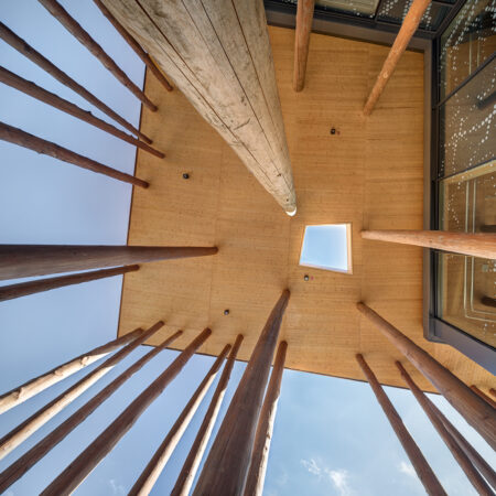 Baumstämme an einem Holzbau tragen ein Vordach