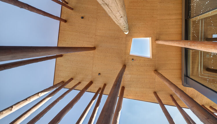 Baumstämme an einem Holzbau tragen ein Vordach