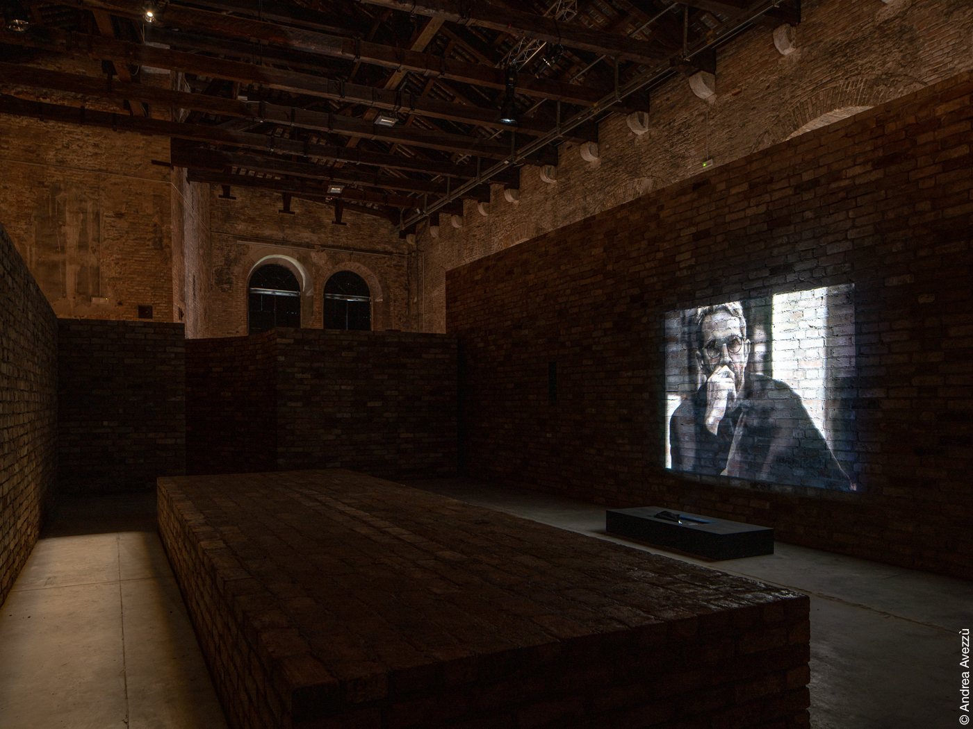 Filmprojektion auf dunklen Ziegelwänden in alter Halle