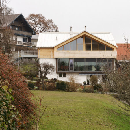 Haus mit hölzernem Obergeschoss vor Kirchturm