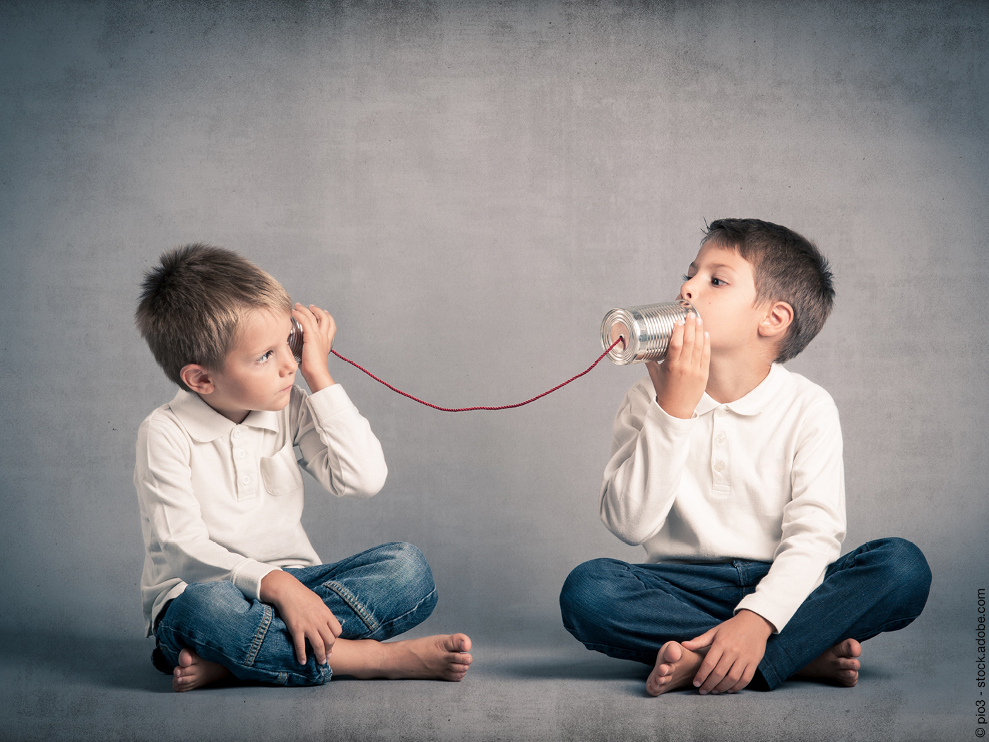 Zwei Kinder die über ein "Büchsentelefon" kommunizieren