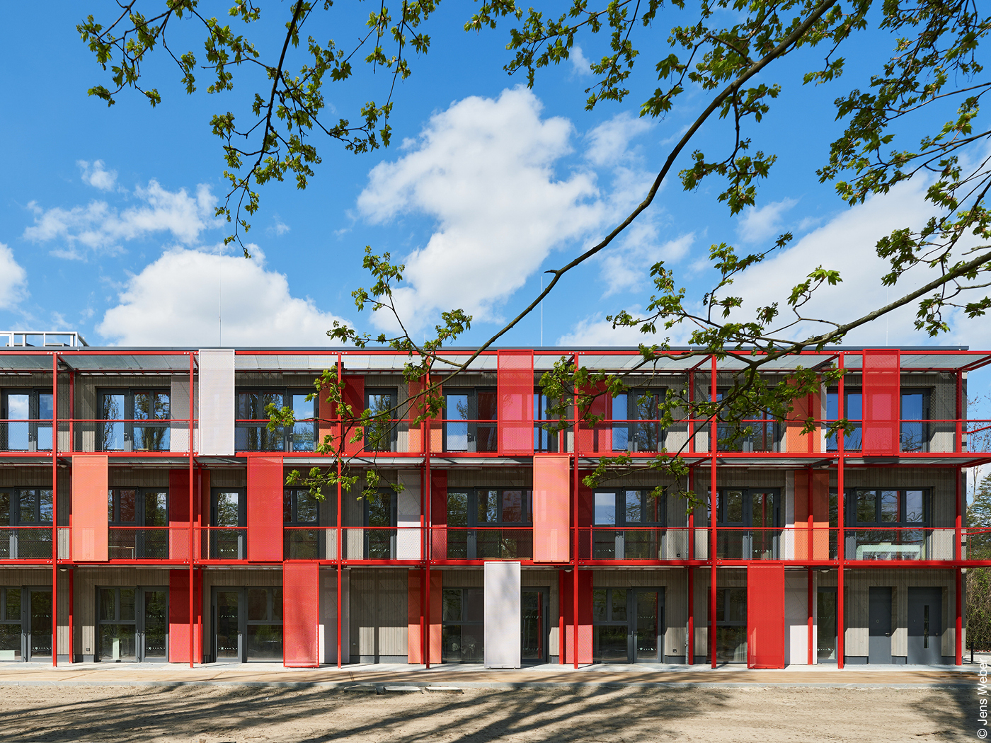 Rotes Gebäude mit vielen Fenstern, Balkonen und Sonnenschutzelementen