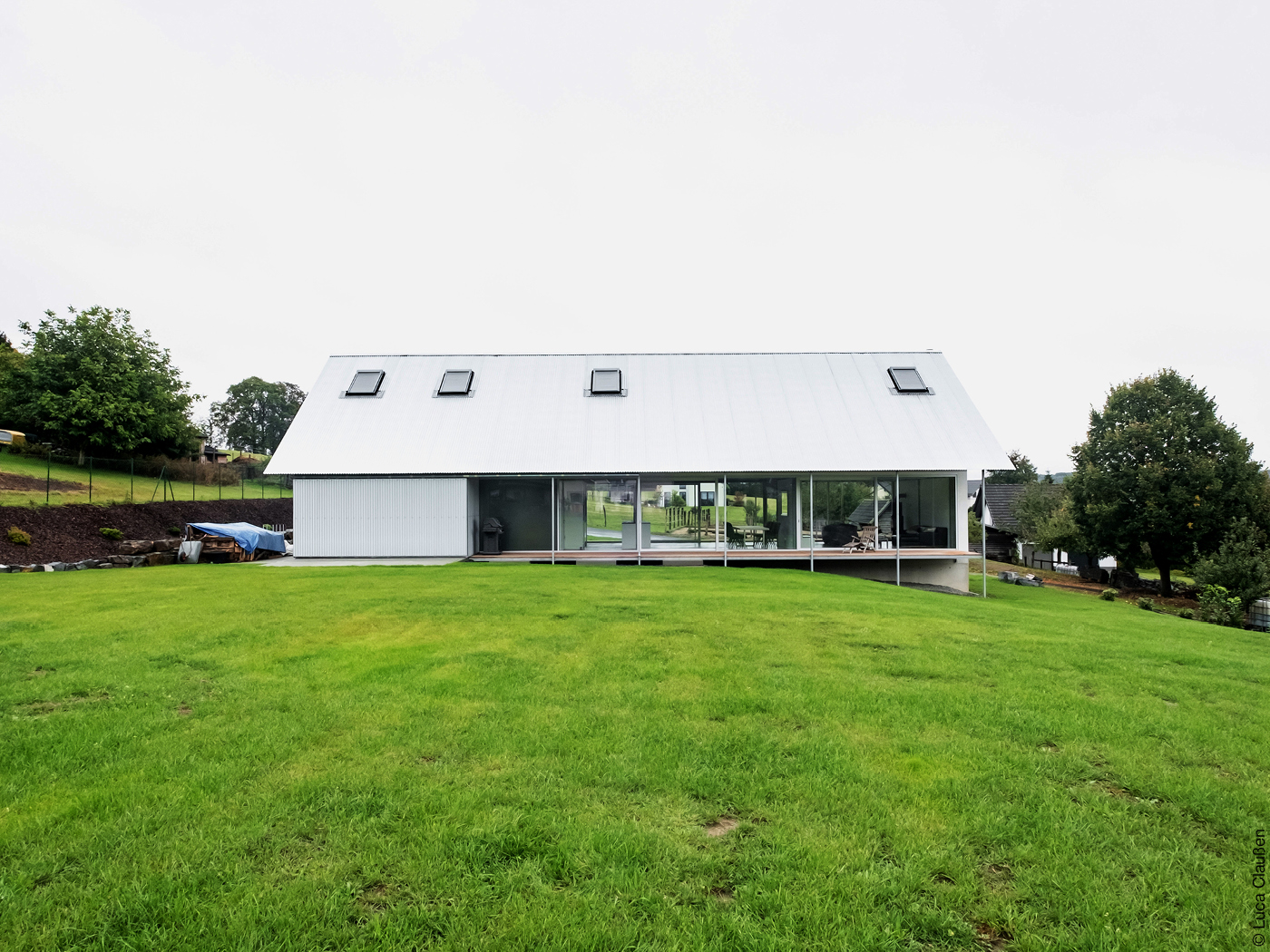 Wohnhaus mit Glasfront und großem Schrägdach auf Wiese