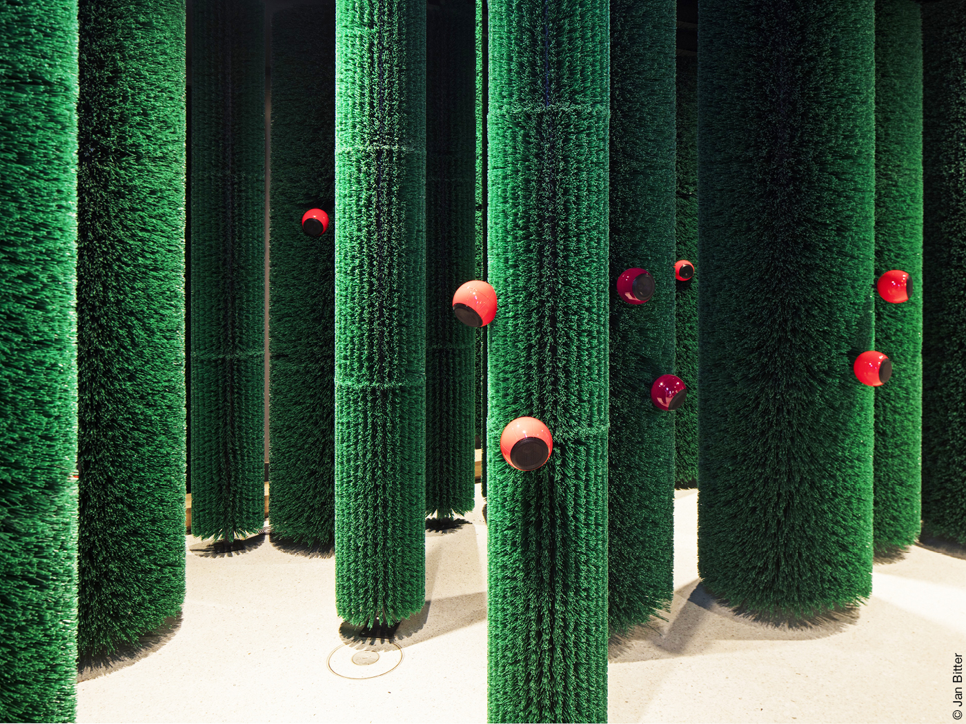 Wald aus grünen Baumstämmen mit roten Lautsprecher-Kugeln