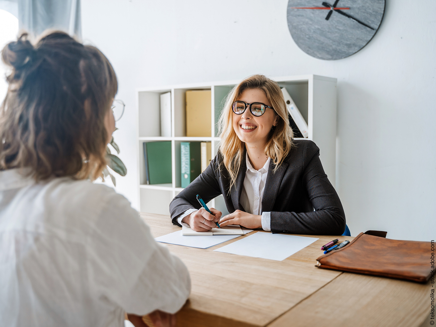 Zwei Frauen unterhalten sich an einem Schreibtisch. Vielleicht sprechen sie über Geld.