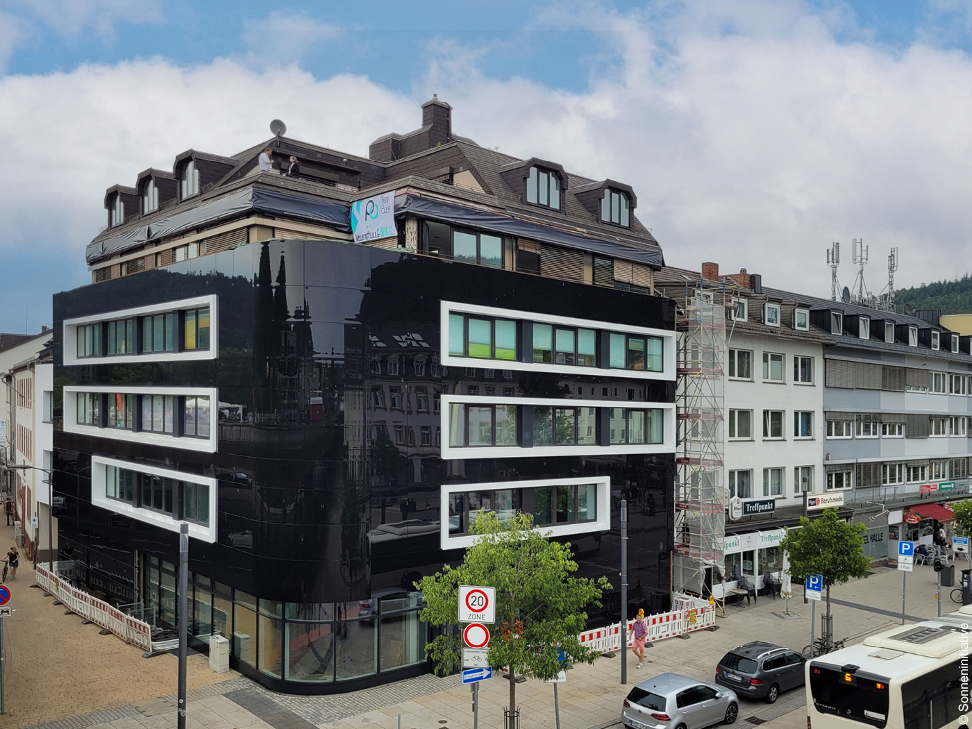 Eckhaus mit glänzend schwarzer Photovoltaik Fassade und großen Fenstern.