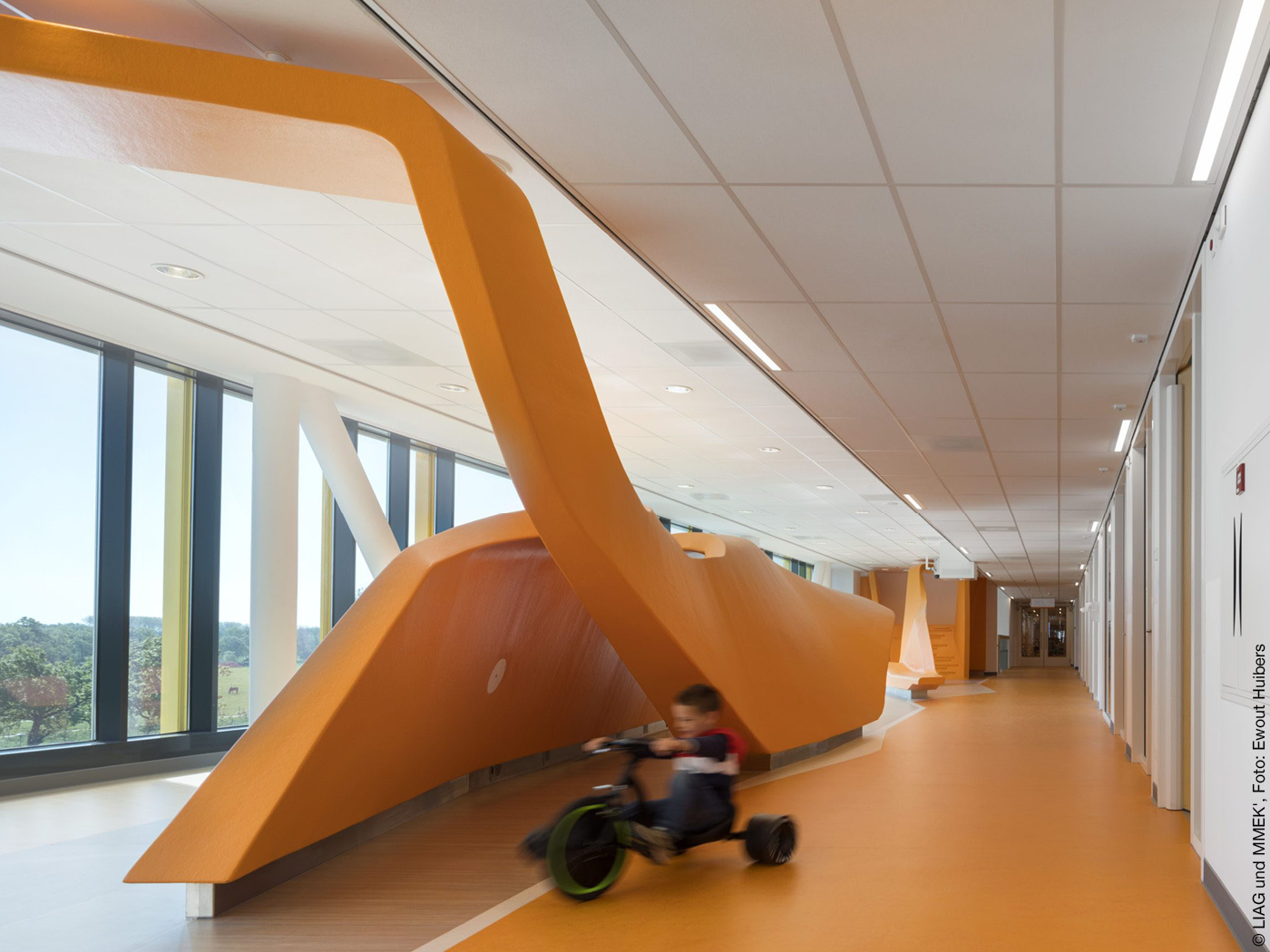 Krankenhausflur mit großen Fenstern und oranger Raumskulptur