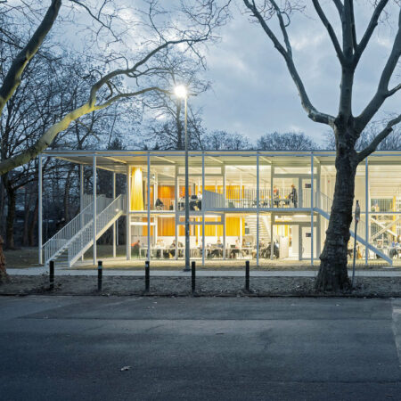 Gläserner Pavillon mit gelben Vorhängen am Abend