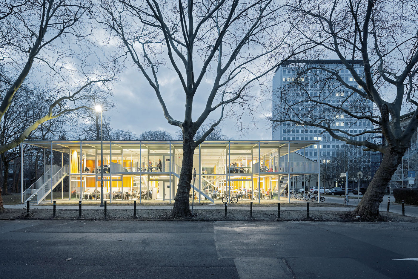 Gläserner Pavillon mit gelben Vorhängen am Abend