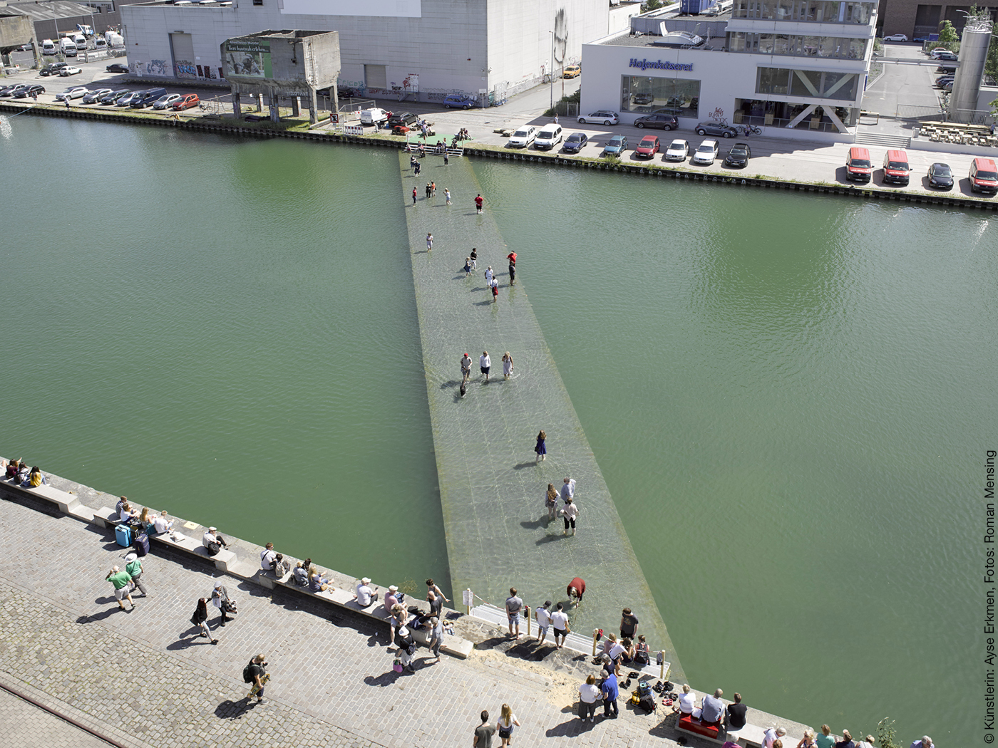 Menschen laufen über einen Steg in einem Hafenbecken