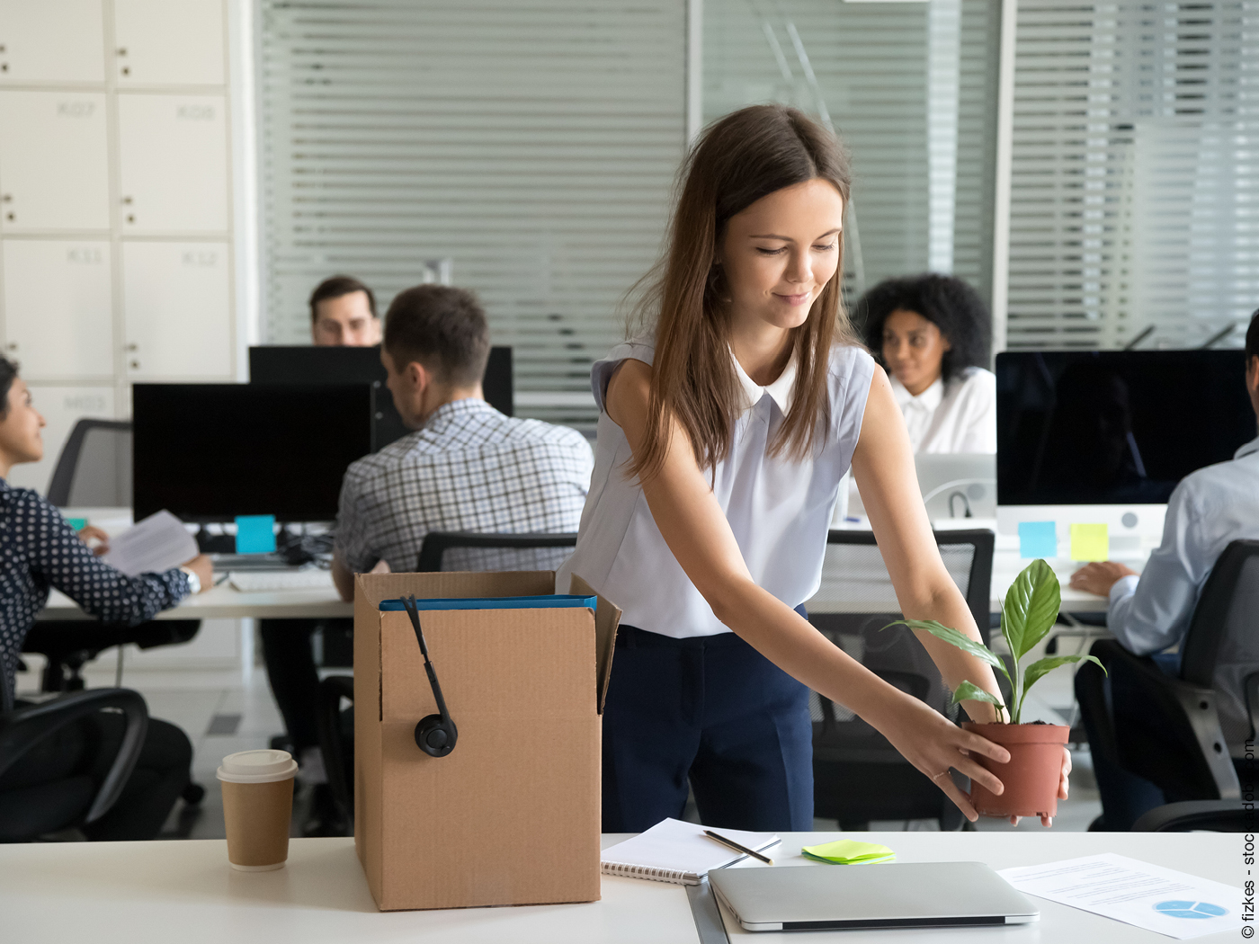 Eine junge Frau richtet sich am Arbeitsplatz ein.