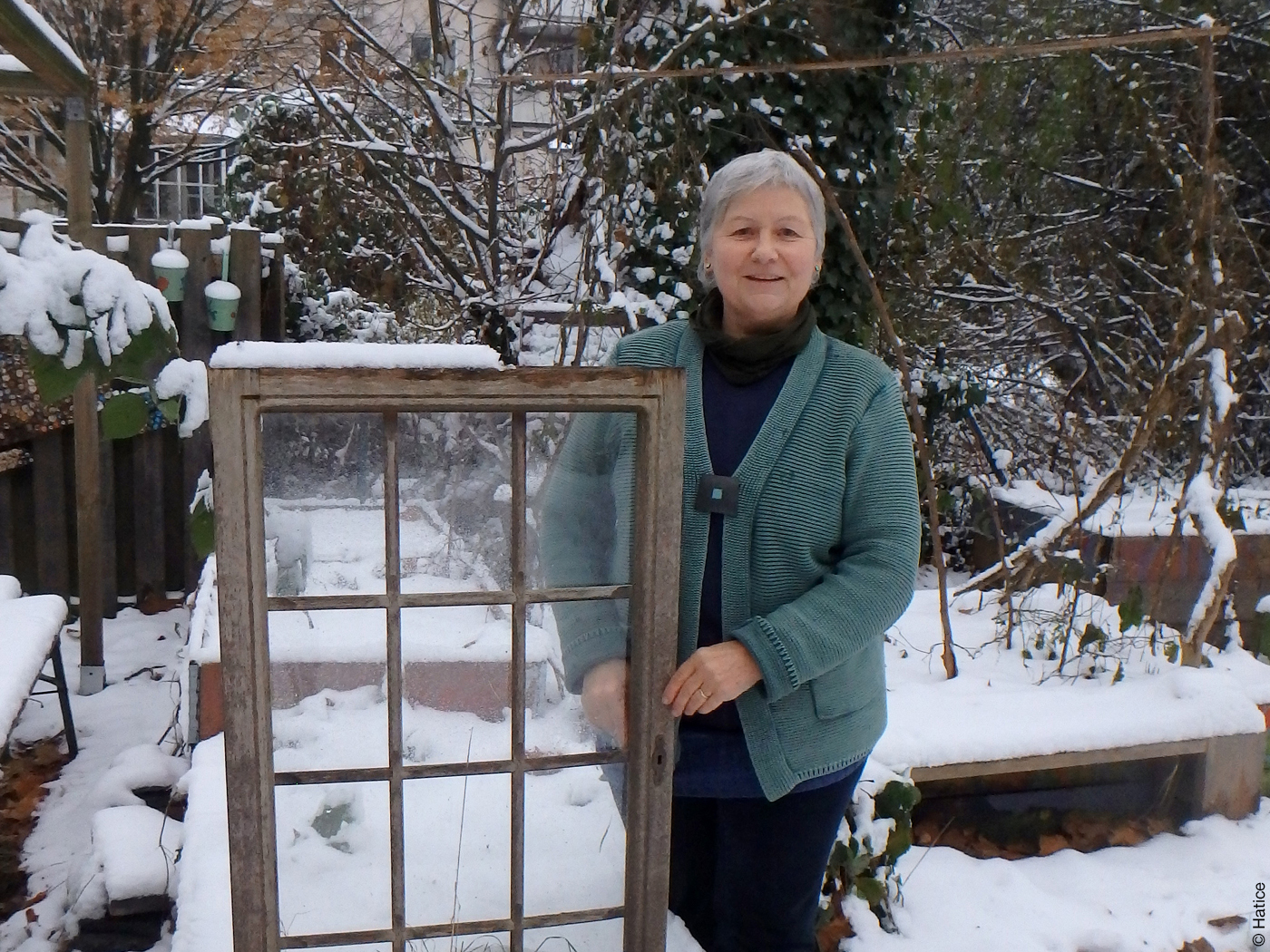 Architektin Ute Dechantsreiter mit einem alten Fenster in einem verschneiten Garten.