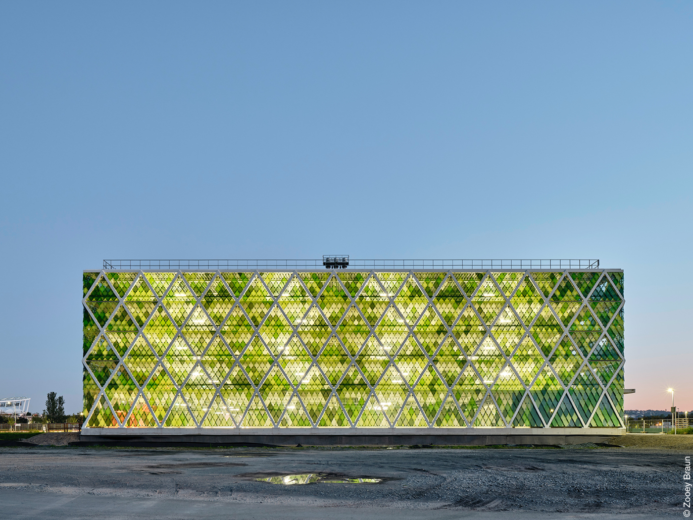 Beleuchtetes Parkhaus mit grünen Fensterscheiben und diagonalem Tragwerk