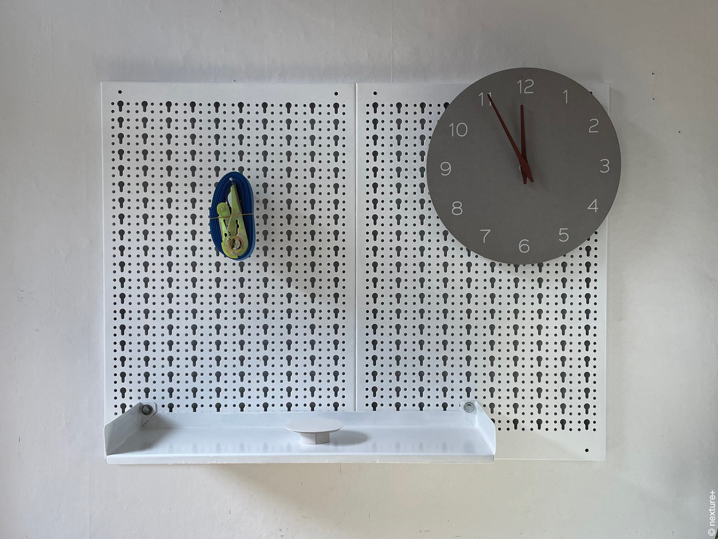 Eine Uhr, ein Spanngurt und das Modell eines runden Tisches.