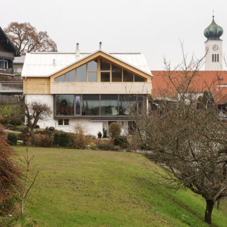 Haus mit hölzernem Obergeschoss vor Kirchturm