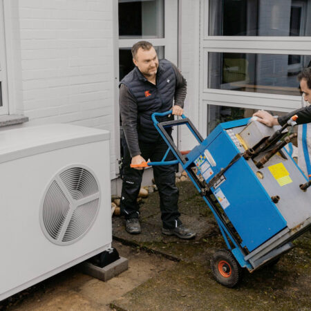 Handwerker tauschen ein altes Heizgerät gegen eine neue Wärmepumpe