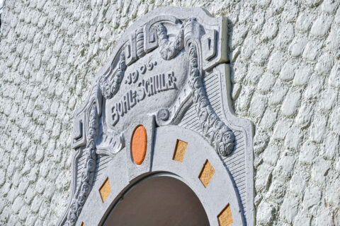 Fassade der Bohlschule in Aalen mit verziertem Stuck und grobem Putz in grau-beige