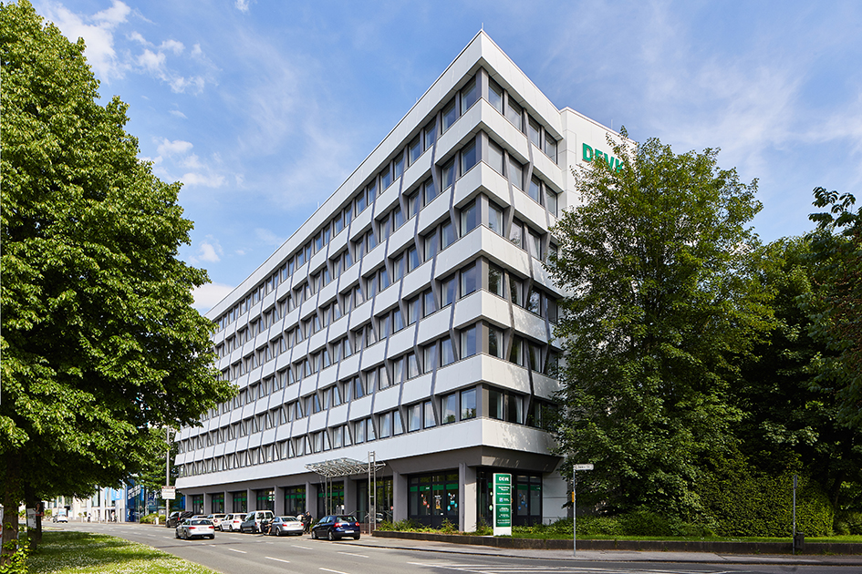 Ein Bürogebäude nach der Fassadensanierung: weiße Grundfarbe und Tiefenstruktur durch Vor- und Rücksprünge.