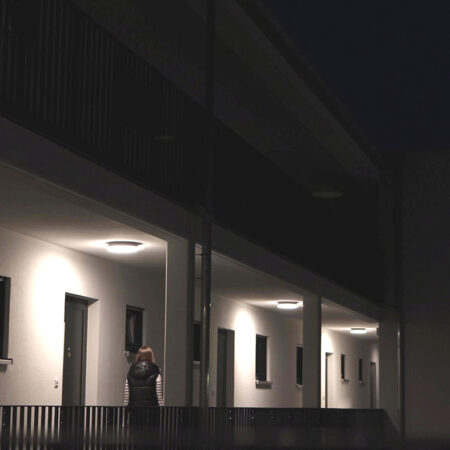 Frau geht über Laubengang zu ihrer Wohnung