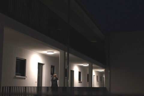 Frau geht über Laubengang zu ihrer Wohnung