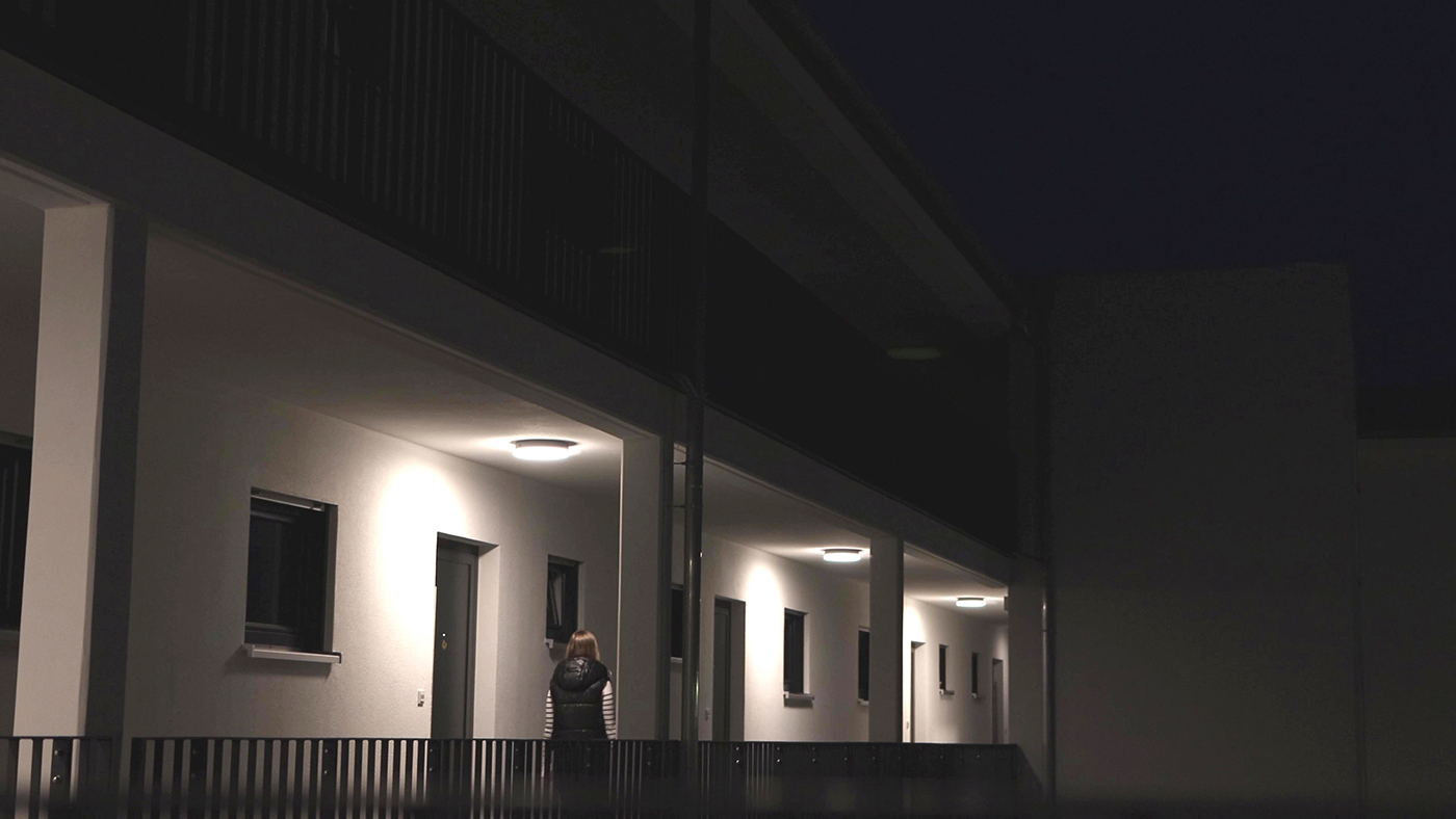 Frau geht über Laubengang zu ihrer Wohnung