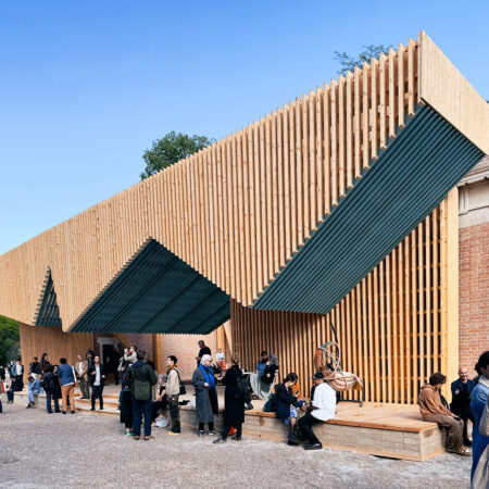 Vordach aus hellbeigem Holz eines Pavillons mit Menschen davor