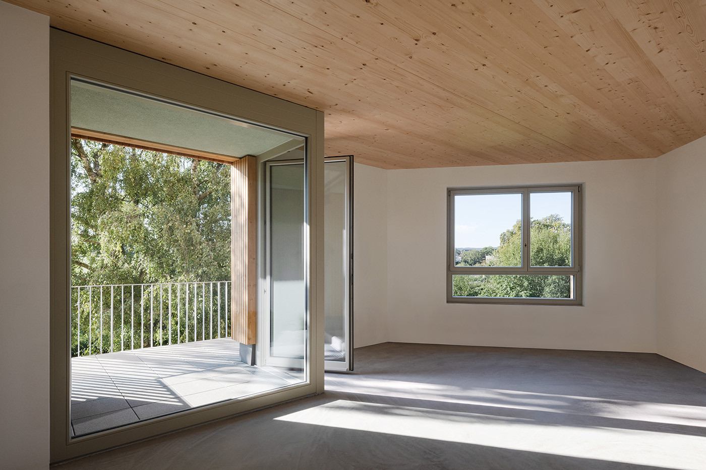 Wohnraum mit großen Fenstern, Holzdecke und einem Balkon